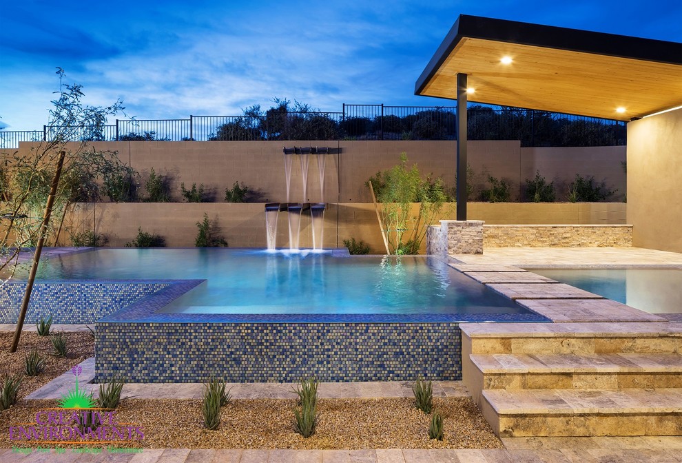 Inspiration for a medium sized traditional back custom shaped infinity swimming pool in Phoenix with a water feature and stamped concrete.