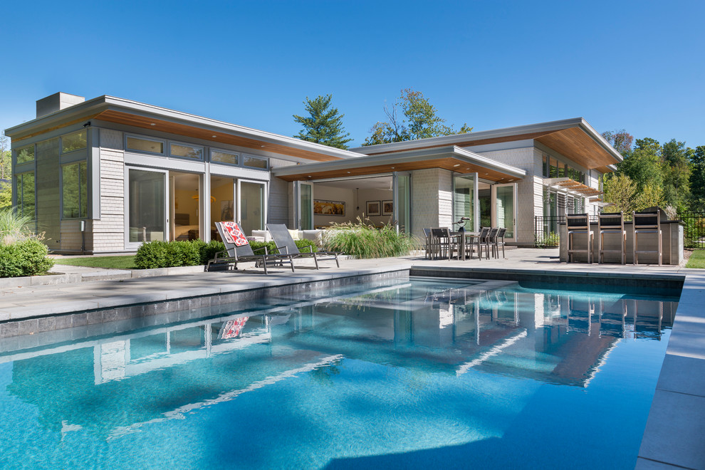 Immagine di una grande piscina monocorsia design rettangolare dietro casa con una vasca idromassaggio e pavimentazioni in cemento