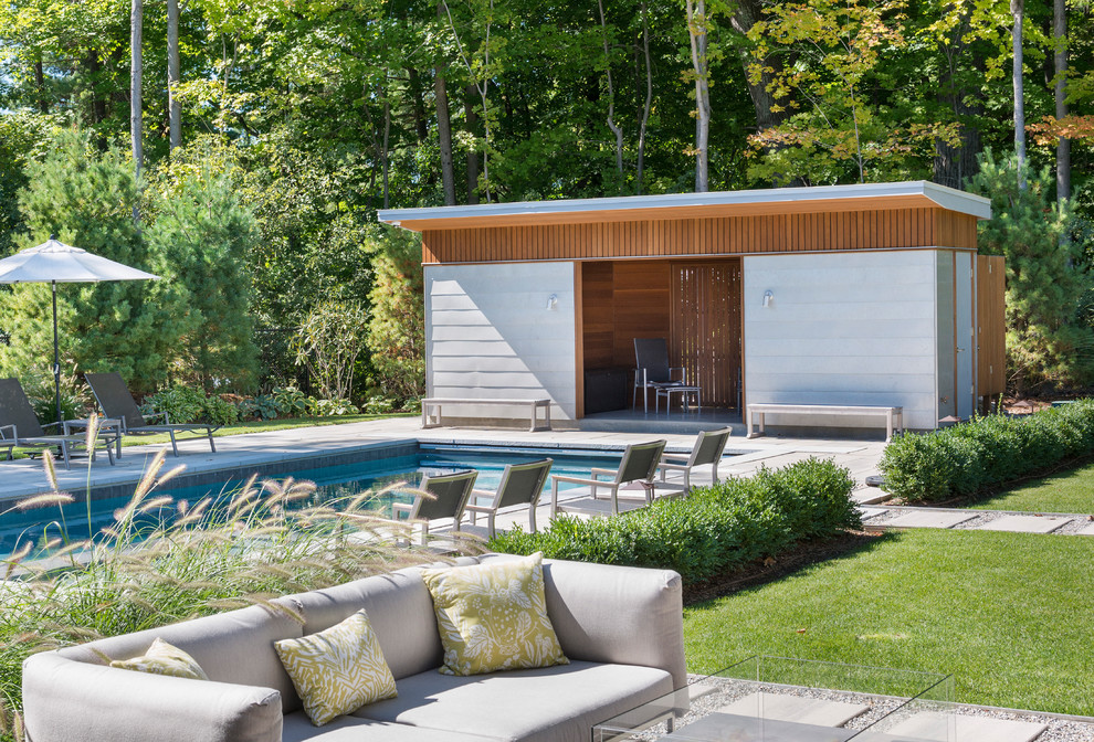 Modelo de casa de la piscina y piscina alargada tradicional renovada pequeña rectangular en patio trasero con adoquines de hormigón