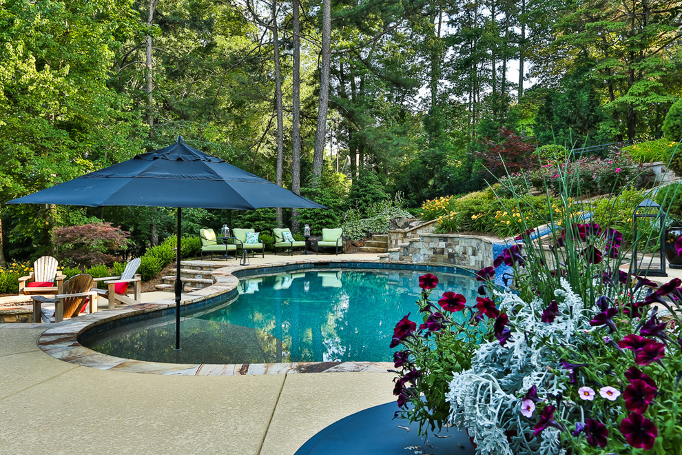 Cette photo montre une grande piscine naturelle et arrière romantique sur mesure avec un toboggan et une terrasse en bois.