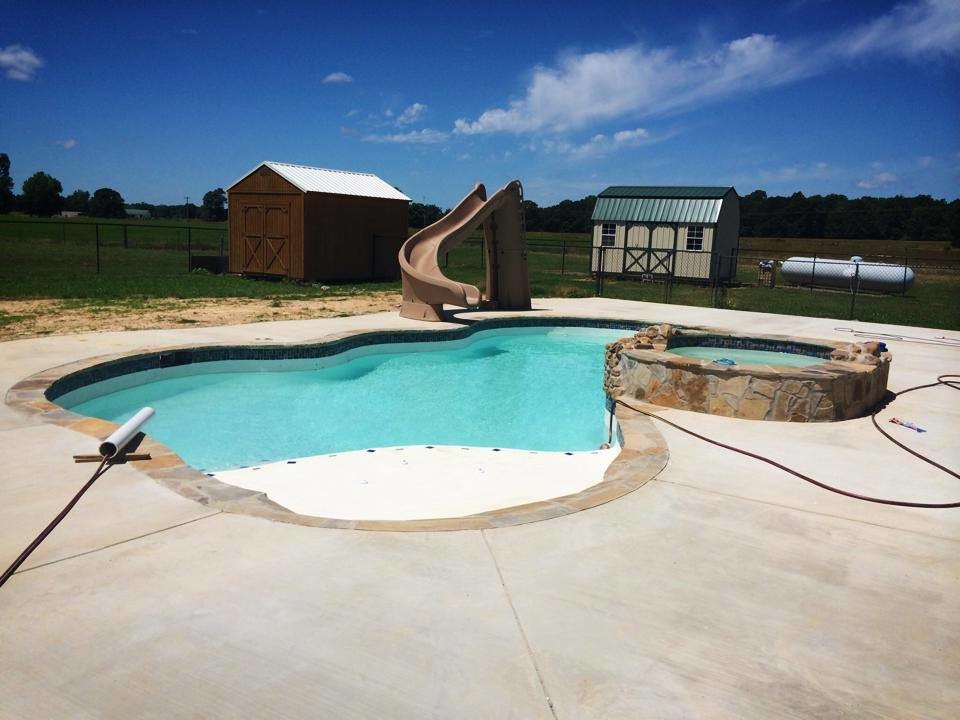 Idee per una piscina classica personalizzata dietro casa con una vasca idromassaggio e lastre di cemento