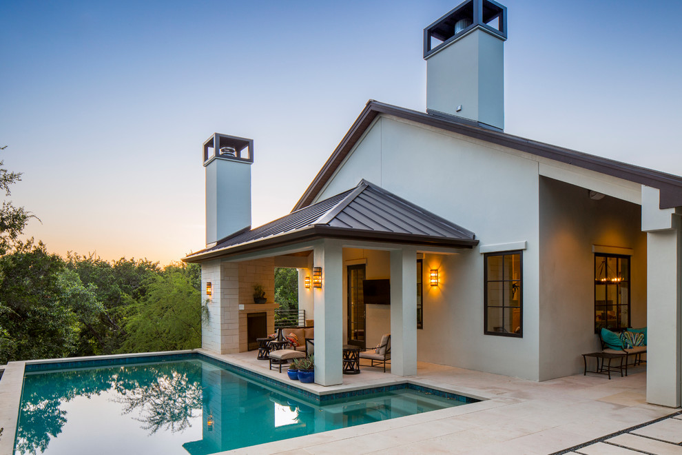 This is an example of a traditional back l-shaped swimming pool in Austin with a pool house and natural stone paving.