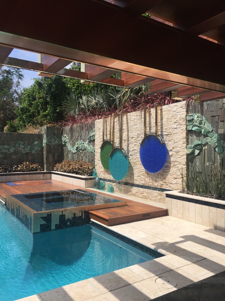 Foto di una grande piscina monocorsia moderna rettangolare dietro casa con una vasca idromassaggio e piastrelle