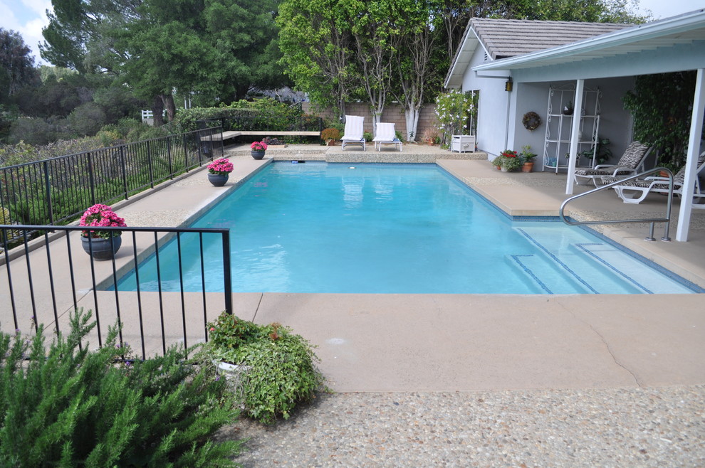 Photo of a medium sized retro back rectangular natural swimming pool in Los Angeles with stamped concrete.