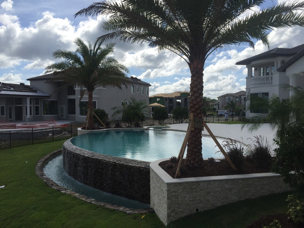 Exempel på en stor exotisk rund pool på baksidan av huset, med spabad och kakelplattor