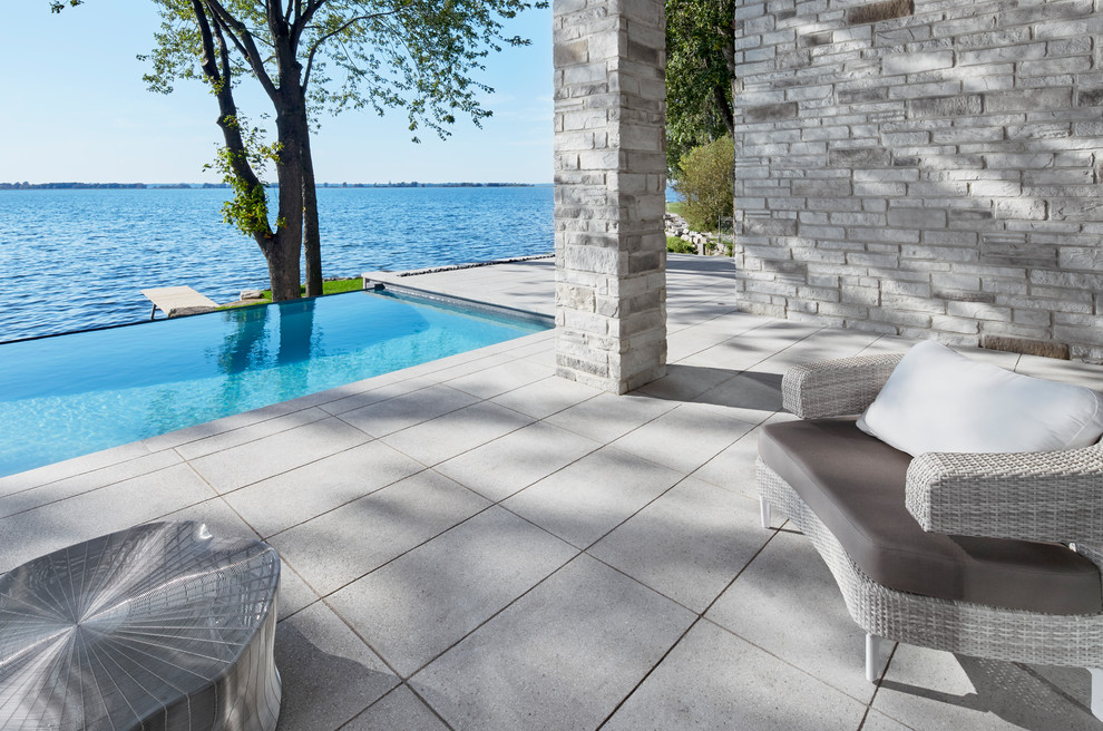 Ispirazione per una grande piscina a sfioro infinito rettangolare dietro casa con pavimentazioni in cemento