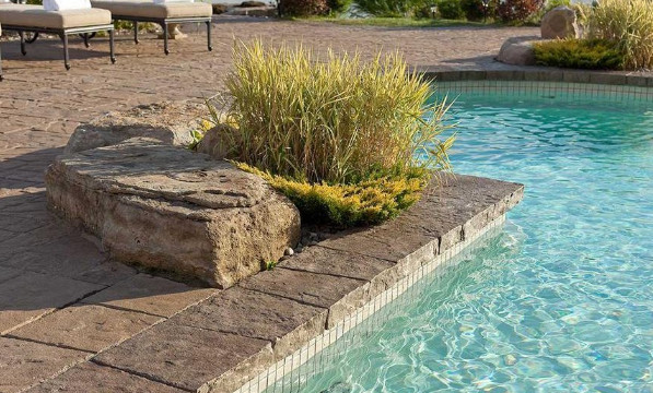 Imagen de piscina con fuente alargada tradicional grande a medida en patio trasero con suelo de hormigón estampado