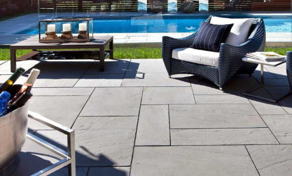 Modelo de piscina con fuente infinita minimalista grande rectangular en patio trasero con suelo de hormigón estampado