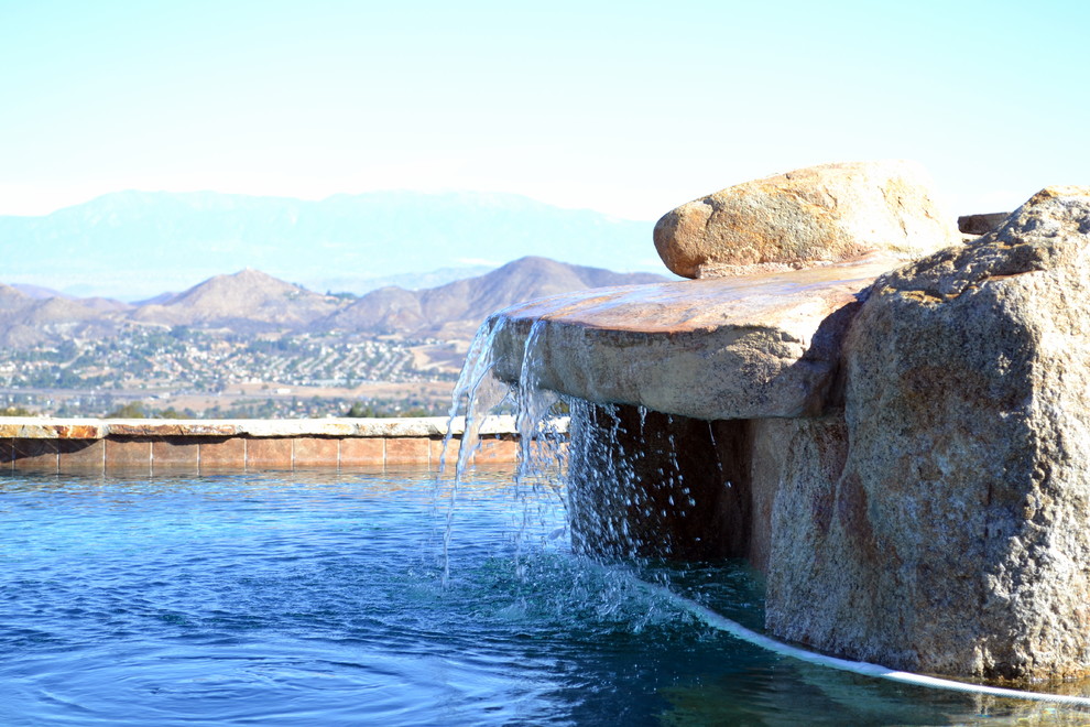 Diseño de piscina con fuente mediterránea extra grande en patio trasero con adoquines de piedra natural
