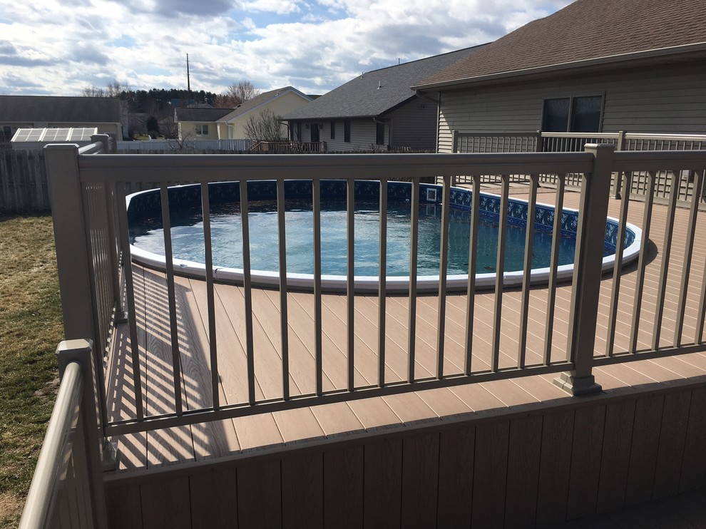 Imagen de piscina tradicional de tamaño medio redondeada en patio trasero con entablado