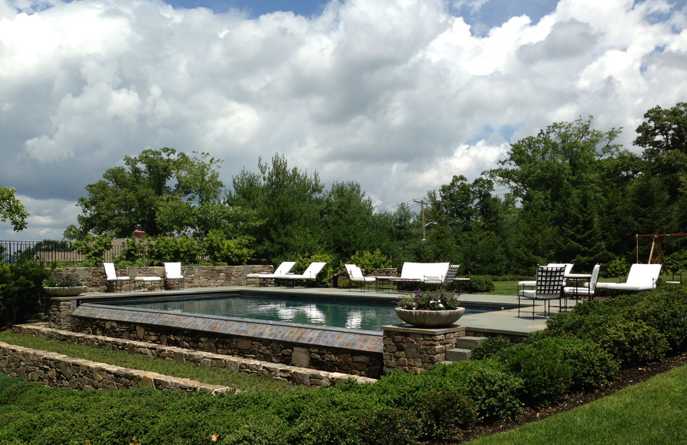 Imagen de piscina con fuente infinita tradicional de tamaño medio rectangular en patio trasero con adoquines de piedra natural