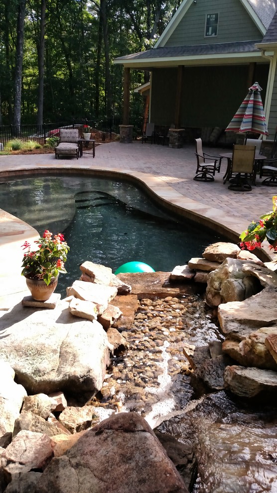 Diseño de piscina con fuente alargada rústica de tamaño medio a medida en patio trasero con adoquines de ladrillo