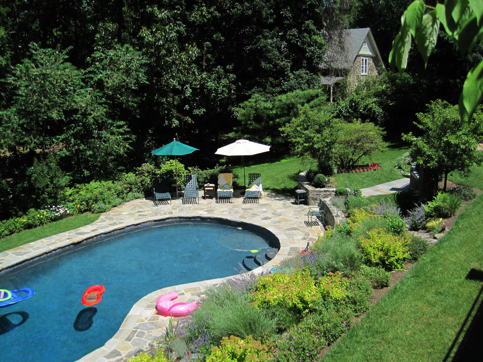 Immagine di una piscina classica con pavimentazioni in pietra naturale