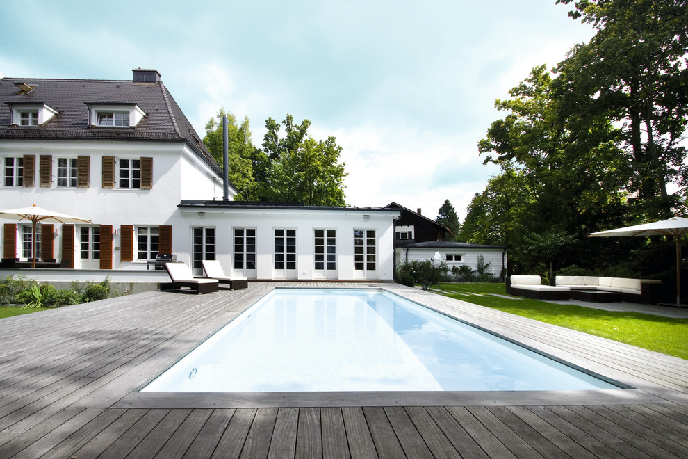 Aménagement d'un grand couloir de nage arrière classique rectangle avec une terrasse en bois.