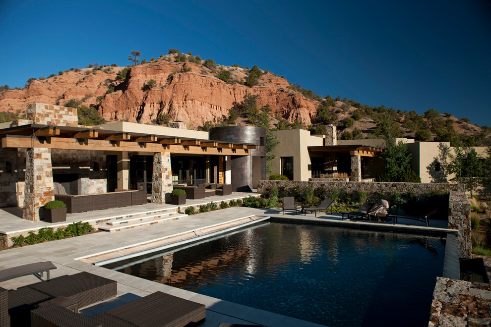 Cette photo montre une très grande piscine à débordement sud-ouest américain rectangle avec des pavés en pierre naturelle.