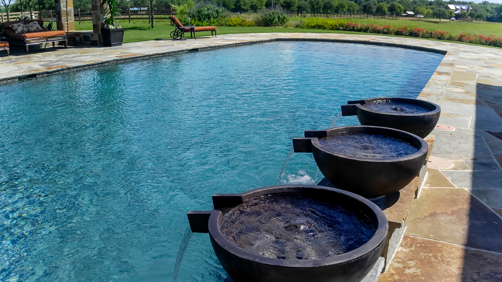 Modelo de piscina con fuente alargada tradicional grande rectangular en patio trasero con adoquines de piedra natural
