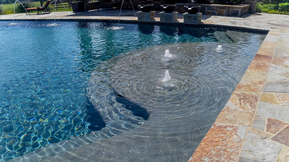Immagine di una grande piscina monocorsia tradizionale rettangolare dietro casa con fontane e pavimentazioni in pietra naturale