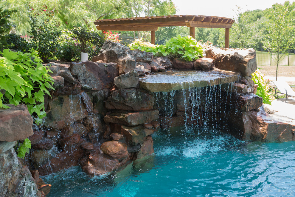 На фото: огромный бассейн произвольной формы на заднем дворе в классическом стиле с покрытием из каменной брусчатки с