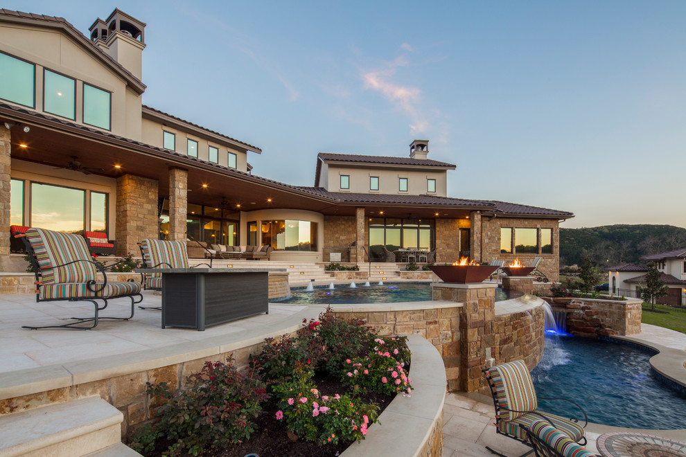 Example of a large tuscan backyard concrete paver and kidney-shaped infinity hot tub design in Austin