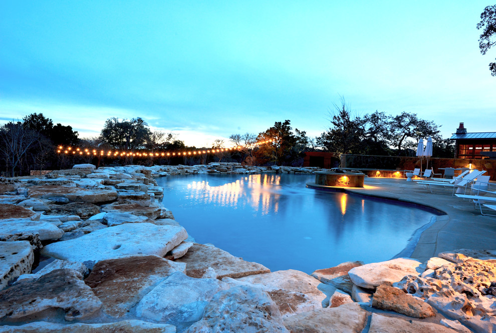 Ejemplo de piscina natural moderna grande tipo riñón en patio con losas de hormigón