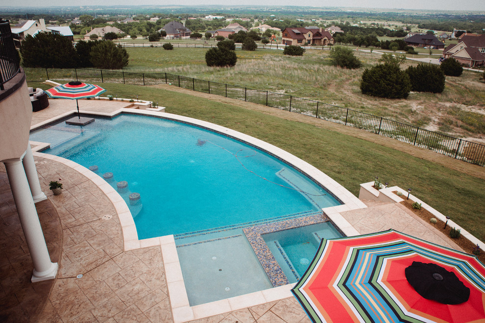 Foto di una grande piscina a sfioro infinito mediterranea personalizzata dietro casa con una vasca idromassaggio e lastre di cemento