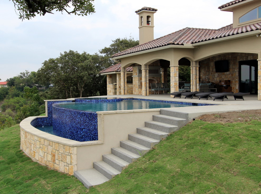 This is an example of a medium sized mediterranean back custom shaped infinity swimming pool in Austin with concrete slabs.