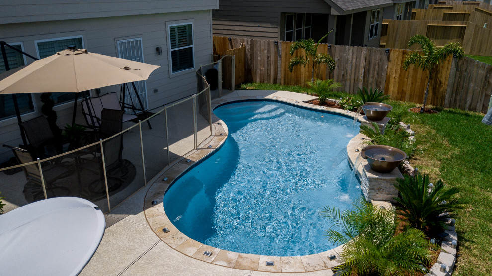 Imagen de piscina tropical pequeña tipo riñón en patio trasero