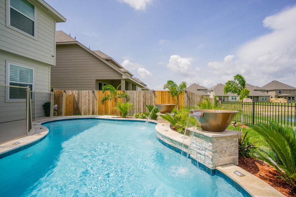Foto de piscina tropical pequeña tipo riñón en patio trasero