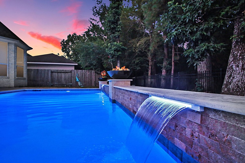 Foto de piscina con fuente alargada actual grande rectangular en patio trasero con adoquines de ladrillo