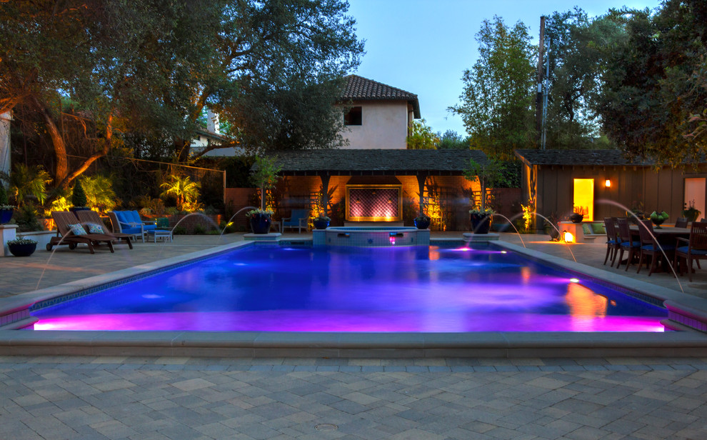 Idee per una grande piscina monocorsia mediterranea rettangolare dietro casa con pavimentazioni in pietra naturale e fontane