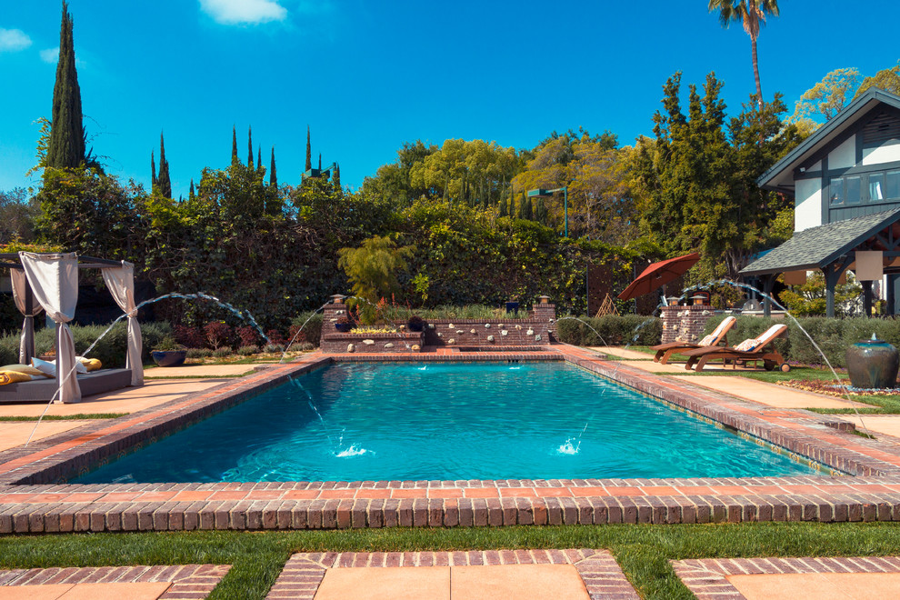 Example of a large farmhouse backyard brick and rectangular lap pool fountain design in Los Angeles