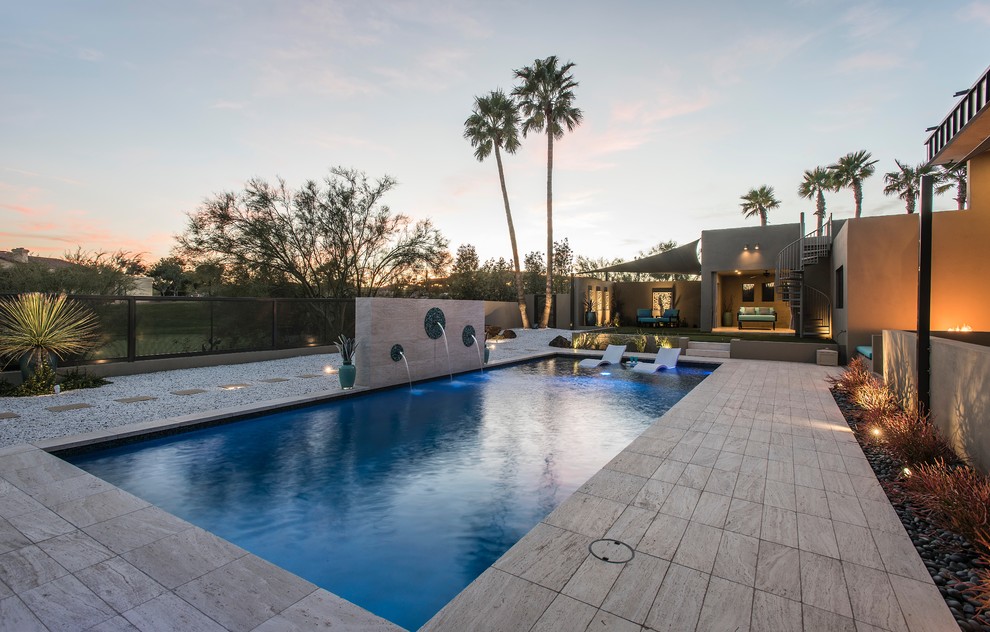 Esempio di una grande piscina monocorsia minimal rettangolare dietro casa con fontane e piastrelle