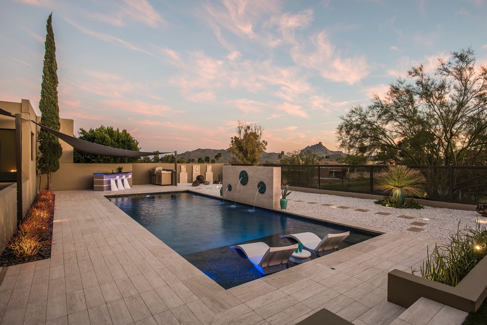 Imagen de piscina con fuente alargada contemporánea grande rectangular en patio trasero con suelo de baldosas