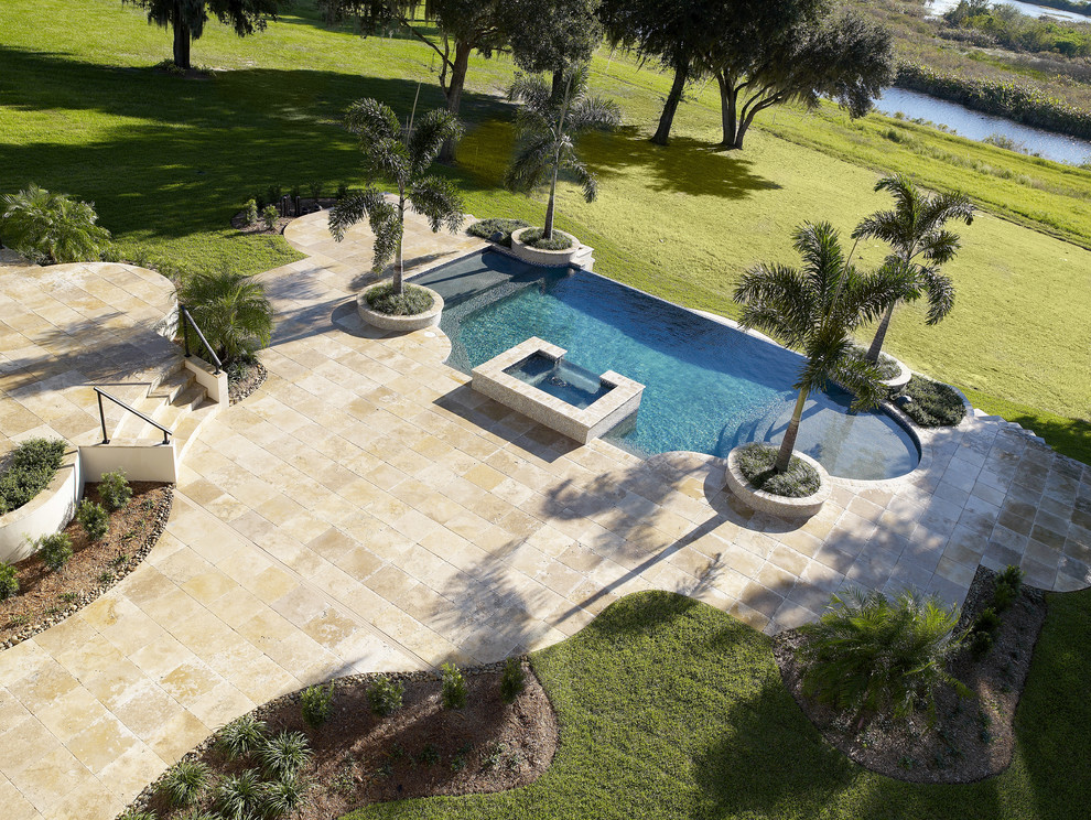 Esempio di una piscina monocorsia mediterranea rettangolare di medie dimensioni e dietro casa con una vasca idromassaggio e pavimentazioni in pietra naturale