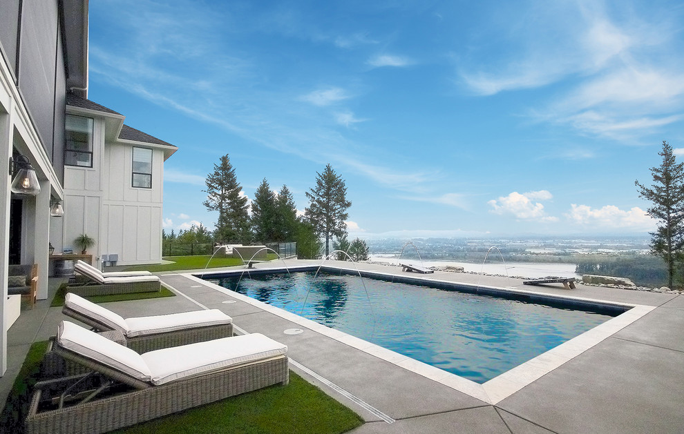 Ejemplo de piscina con fuente alargada campestre grande rectangular en patio trasero con suelo de hormigón estampado
