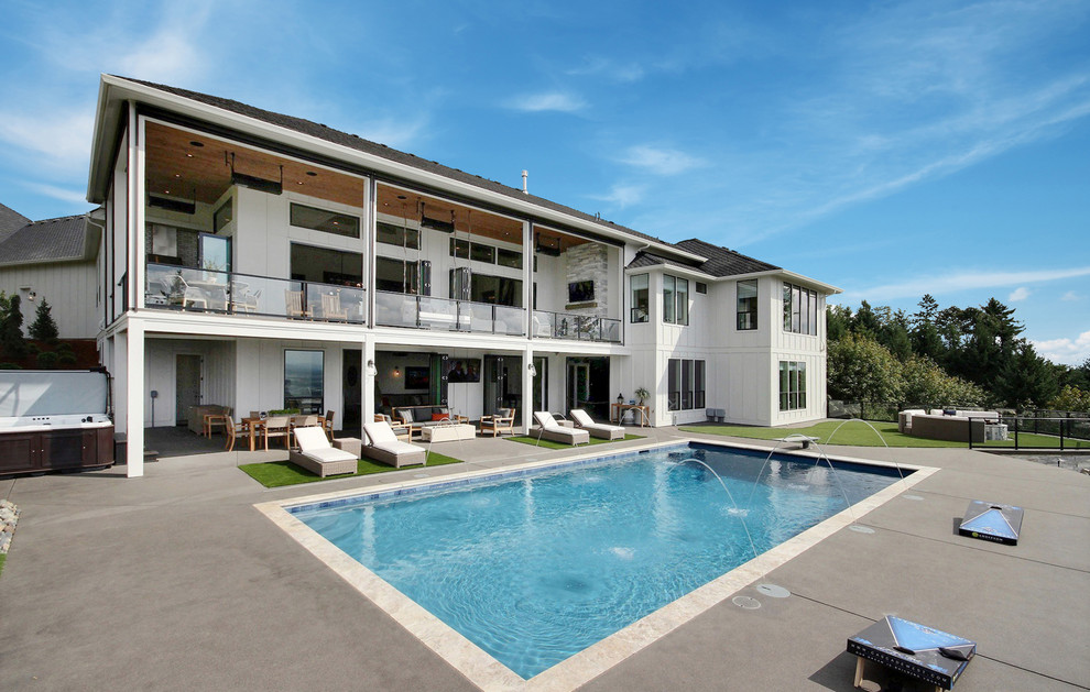 Ejemplo de piscina con fuente alargada de estilo de casa de campo grande rectangular en patio trasero con suelo de hormigón estampado