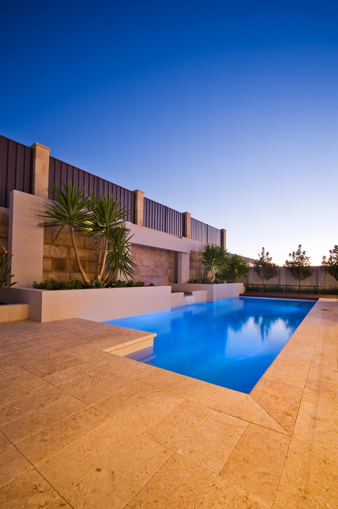 Esempio di una piscina monocorsia minimalista rettangolare dietro casa con fontane e pavimentazioni in pietra naturale