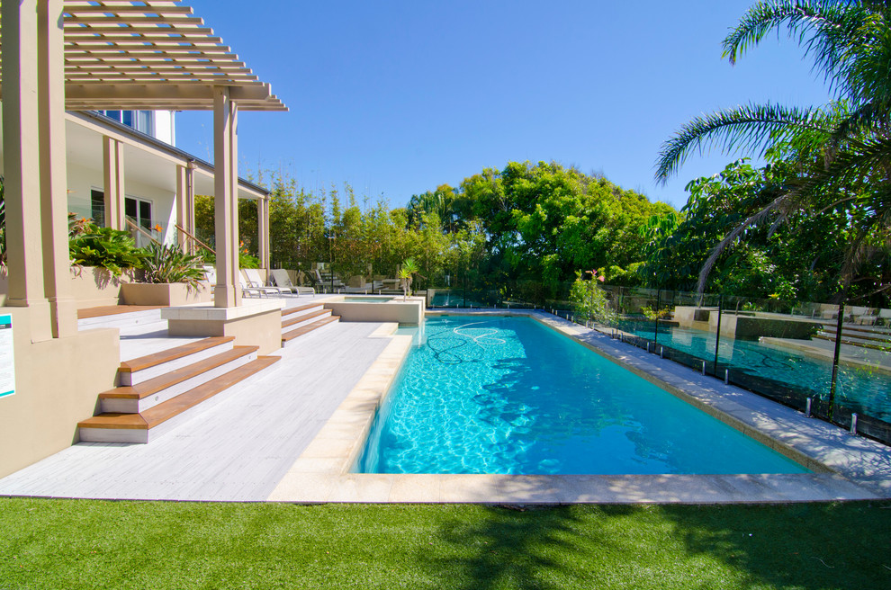 Diseño de piscina con fuente alargada actual grande rectangular en patio trasero con entablado