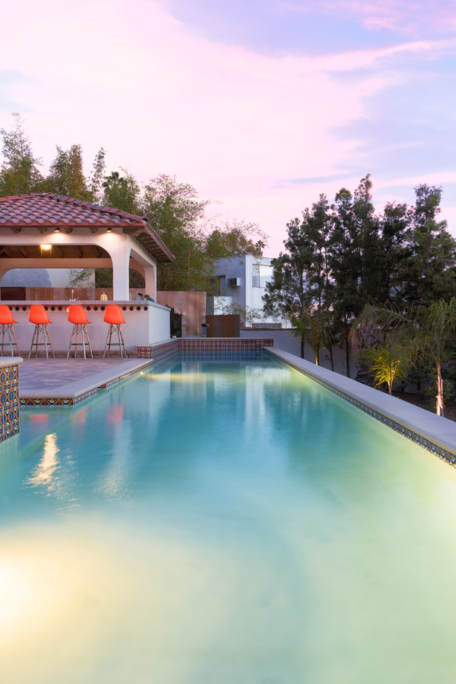 Design ideas for a mediterranean back custom shaped hot tub in Los Angeles with concrete paving.