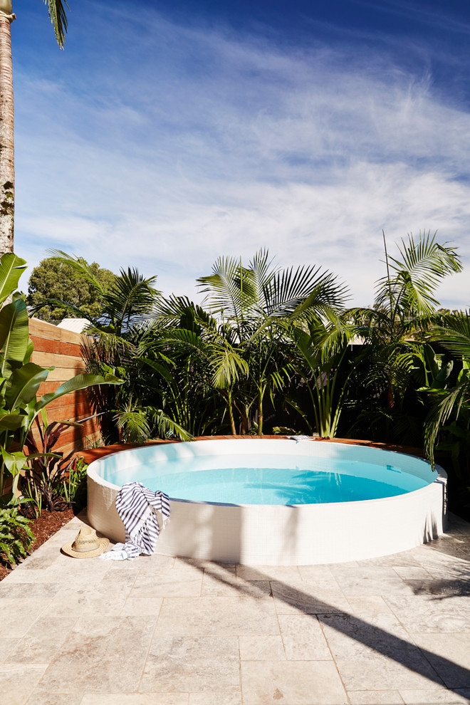 Diseño de piscina elevada contemporánea de tamaño medio redondeada en patio trasero con adoquines de piedra natural