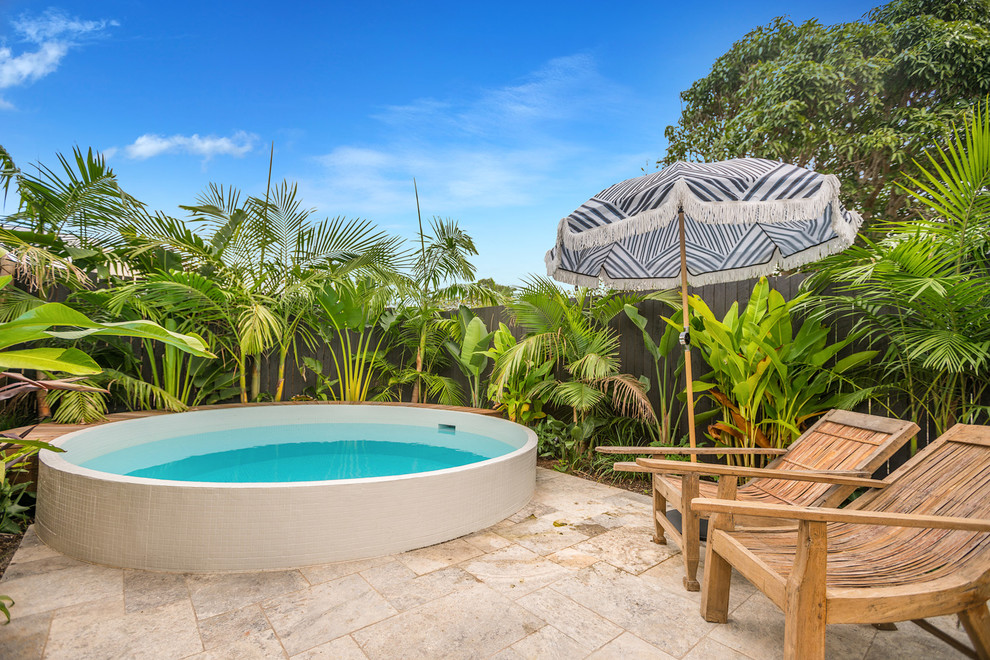 Modelo de piscina elevada marinera redondeada en patio trasero con adoquines de piedra natural