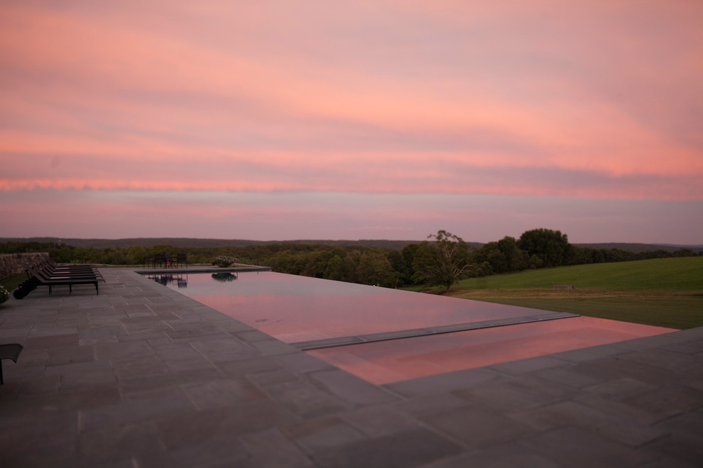 Foto de piscina infinita de estilo de casa de campo grande rectangular en patio trasero con adoquines de piedra natural