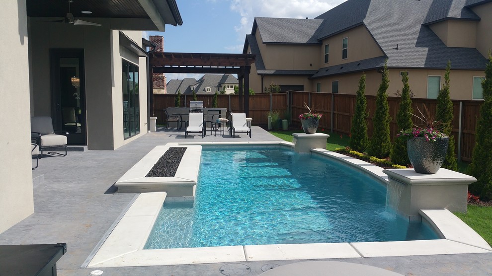 Imagen de piscina con fuente alargada actual grande rectangular en patio trasero con losas de hormigón