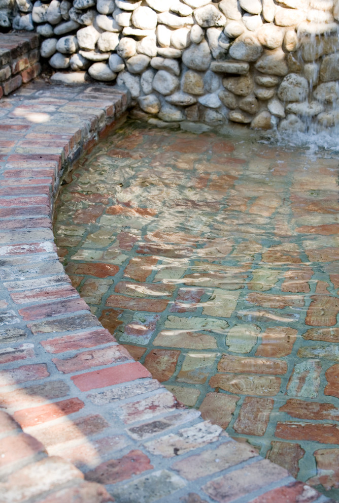 This is an example of a medium sized rustic back custom shaped natural hot tub in Austin with brick paving.