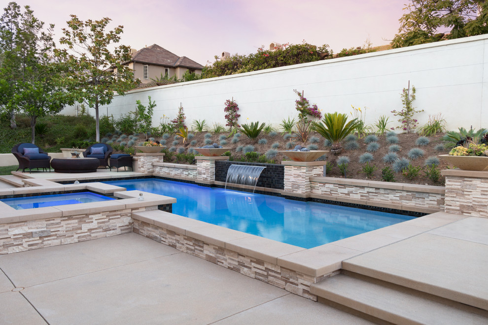 Ispirazione per una piscina mediterranea rettangolare dietro casa con una vasca idromassaggio e lastre di cemento
