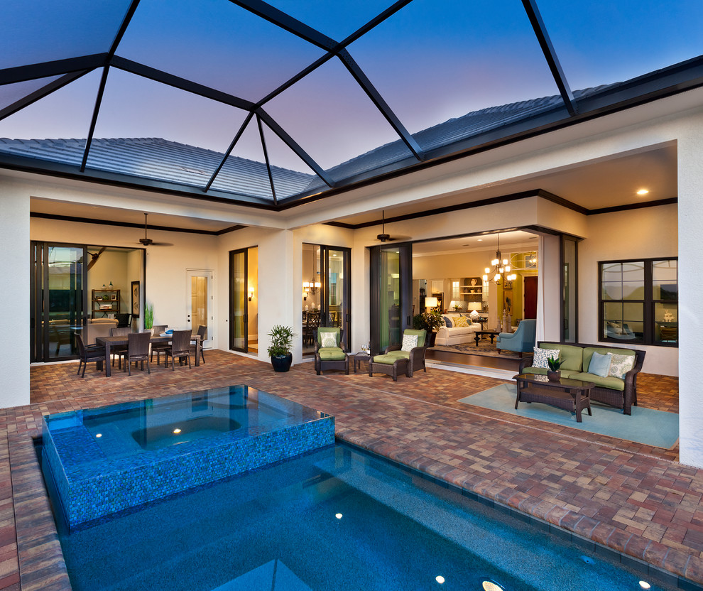 Foto di una grande piscina monocorsia design rettangolare dietro casa con pavimentazioni in mattoni e una vasca idromassaggio