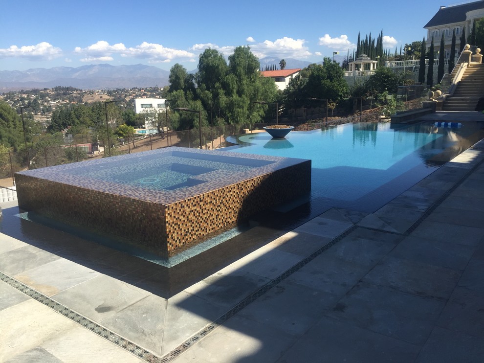 Foto de piscinas y jacuzzis infinitos actuales grandes a medida en patio trasero con suelo de hormigón estampado