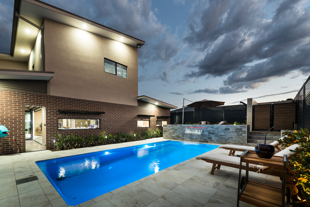 Foto de piscina con fuente alargada contemporánea de tamaño medio rectangular en patio trasero con suelo de baldosas