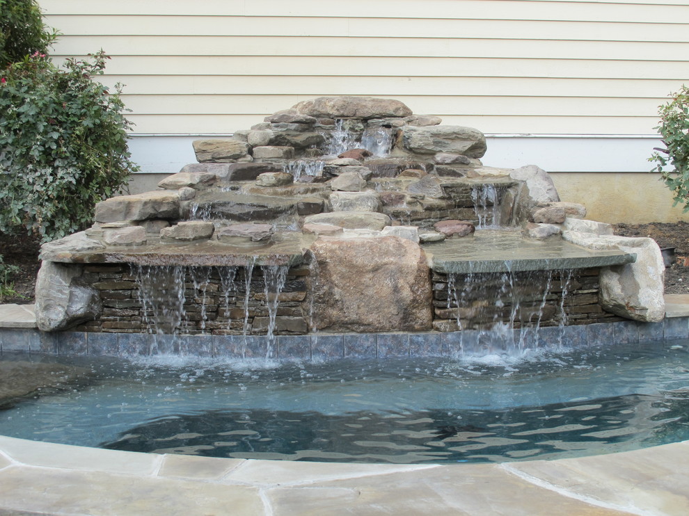 Стильный дизайн: естественный бассейн среднего размера, произвольной формы на заднем дворе в стиле неоклассика (современная классика) с джакузи и покрытием из каменной брусчатки - последний тренд