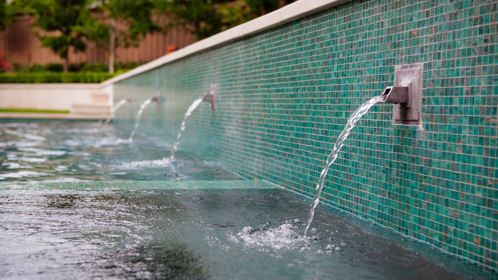 Klassischer Pool hinter dem Haus in L-Form mit Wasserspiel und Natursteinplatten in Dallas